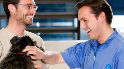 two men holding dog
